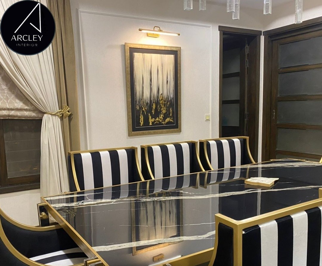 Black marble dining table with black and white striped banquette seating and brass trim